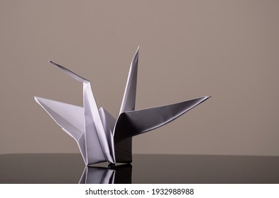 White paper crane on gray background. Play origami, create animal figures with a single piece of paper, without using scissors or glue. Art and culture of Japanese origin