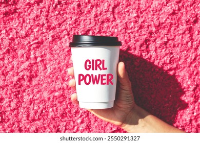 white paper cup for hot drink with inscription text girl power in female hand on pink textured wall background. - Powered by Shutterstock