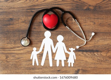 White paper cut of family, stethoscope and heart on wooden background top view. Health medical insurance concept.