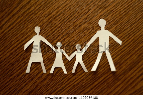   White Paper Cutout Of A Family On Wooden\
Background                            \
