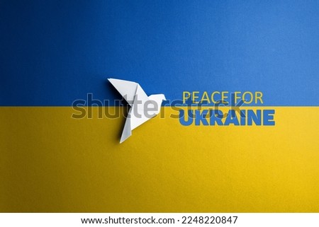 white paper dove bird on background of flag of ukraine with blue yellow color with words peace for Ukraine