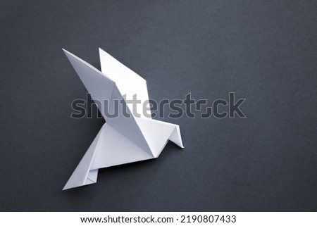 White paper dove origami isolated on a blank grey background.