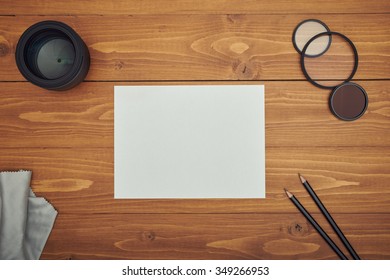 White paper and pencil on wooden table with camera lens - Shutterstock ID 349266953