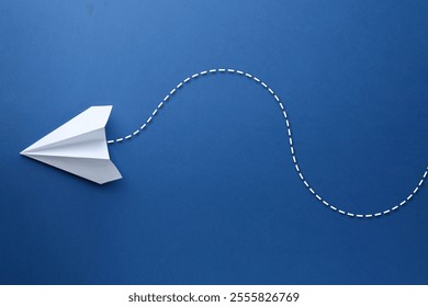 White paper plane with flight path on blue background. Dashed line for trajectory
