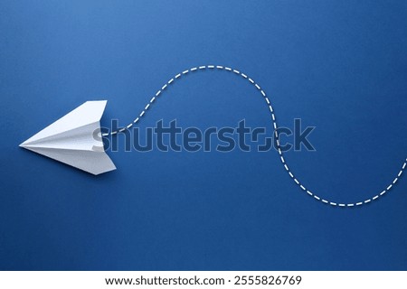 White paper plane with flight path on blue background. Dashed line for trajectory