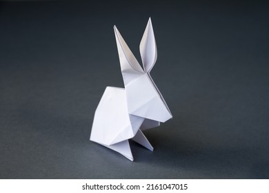 White paper rabbit origami isolated on a blank grey background.