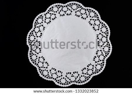 White paper round lace doily, on black background.
