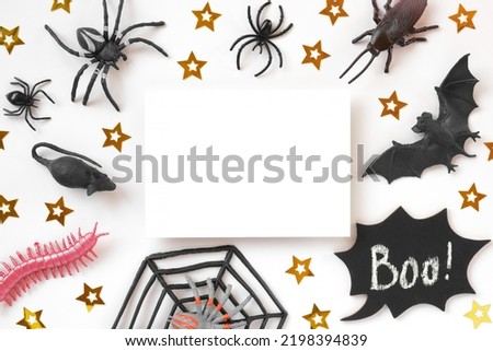 White paper sheet on Halloween background with black bats, spiders and golden stars. Modern Holiday Mock up. Halloween party invitation. Flat lay, top view, copy space. Thanksgiving fall decoration