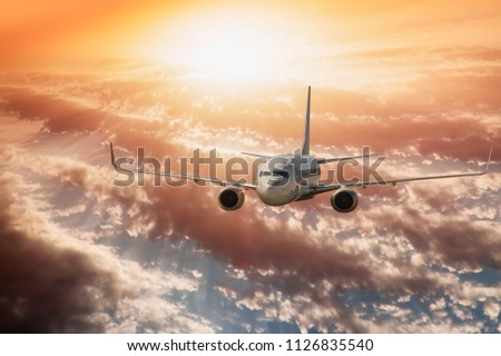 White passenger airplane in the clouds with dramatic sunset - Travel by air transport
