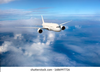 White passenger plane flies over the clouds. Front view of aircraft. Travel and transportation concept.