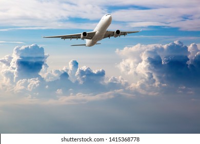 White passenger plane in flight. Aircraft flying high in the blue sky above the clouds. The aircraft is located at the top of the frame.