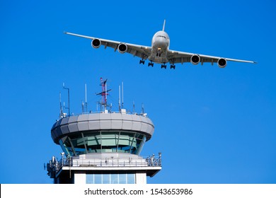 White passenger plane in flight. Aircraft flies over the Air Traffic Control tower (ATC tower).