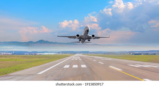 Weißes Passagierflugzeug fliegt von Flughafen aus über Startbahn 