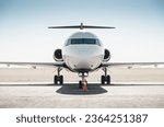 White passenger regional jet facing the camera. Symmetric frontal close-up view of passenger T-tail plane on a ground on a sunny day - bright afternoon sun lighting from the back