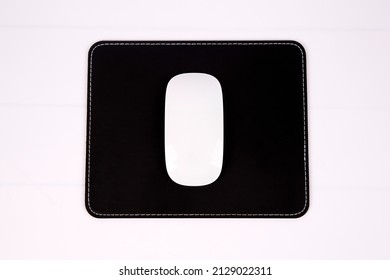 White Pc Mouse On A Black Leather Square Mousepad On White Background