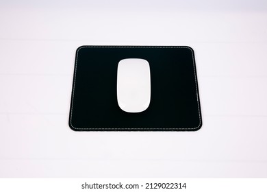 White Pc Mouse On A Black Leather Square Mousepad On White Background