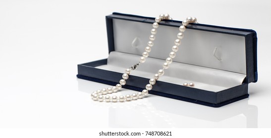 White Pearl Necklace In A Black Velvet Box On Isolated White Background.