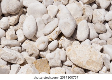White pebbles background texture. Smooth round stones. Zen garden, spa, and meditation concept. Beach pebble stones. Perfect for a relaxing background or for use in a spa or meditation setting.