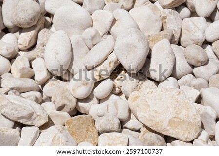 White pebbles background texture. Smooth round stones. Zen garden, spa, and meditation concept. Beach pebble stones. Perfect for a relaxing background or for use in a spa or meditation setting.