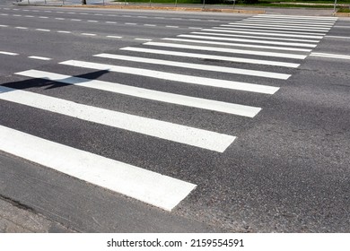 White pedestrian crosswalk across the road with asphalt pavement. Crosswalk road surface marking. Diagonal. Close up