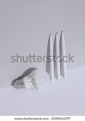 White pens and light bulb on a white background with shadow. Creative idea. Minimal business concept. Conceptual still life