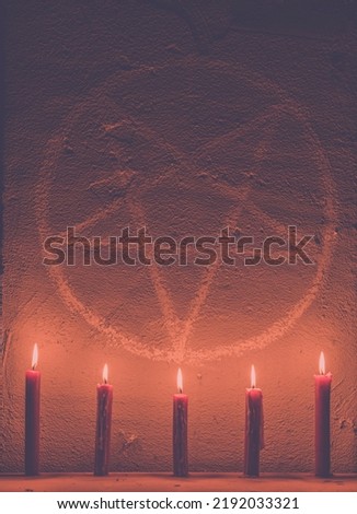 White pentagram symbol on concrete wall. Satanic altar illuminated with candles. Dark background. Scary, mystical occultism 