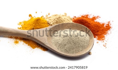 White pepper powder in wooden spoon with cayenne pepper, ginger and turmeric ground isolated on white
