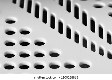 White perforated plastic surface with selective focus. Abstract background