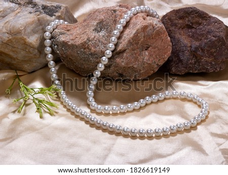 White perls neckless with marble stone on pink silk cloth 