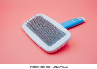 White Pet Glooming Comb And Brush For Dog And Cat Hair In Blue Handle For Pet Salon Isolated On Pink Background