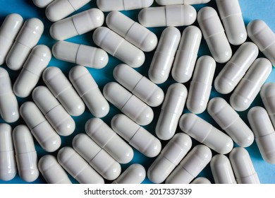 White pharmaceutical pills with colostrum on blue background close-up. Medical background, selective focus