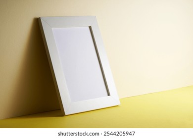 white picture frame leaning against yellow wall        