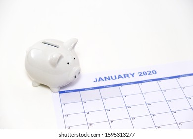 White Piggy Bank On January 2020 Monthly Calendar On White Background. Concept For Money Saving Plan, Financial Accounting, Or New Year Resolution