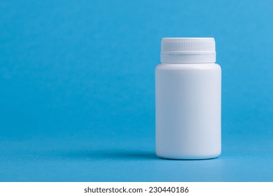 White Pill Bottle Against Blue Background.