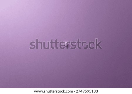 White pill resting on a solid purple background, illustrating focus on health and medicine