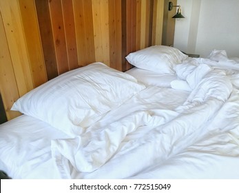 White Pillow And Messy Blanket On Bed With Wooden Headboard. 