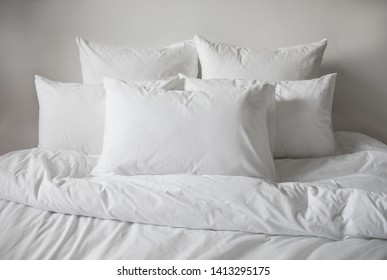 White pillows, duvet and duvet case in a bed. White bed linen on a white bed. Bedroom with bed and linen.