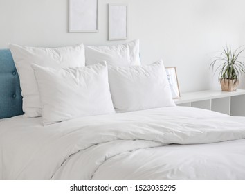 White pillows, duvet and duvet case on a blue bed. White bed linen on a blue sofa. Bedroom with bed and bedding and poster frame mock up on the wall. Left side view. - Shutterstock ID 1523035295