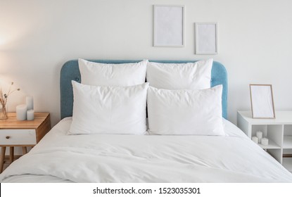 White Pillows, Duvet And Duvet Case On A Blue Bed. White Bed Linen On A Blue Sofa. Bedroom With Bed And Bedding And Poster Frame Mock Up On The Wall. Front View.