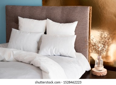 White Pillows, Duvet And Duvet Case On A Bed With Brown Headboard. White Bed Linen On The Sofa. Bedroom With Bed, White Bedding, Nice Posy On The Bedside And Colored Wall. Right Side View.