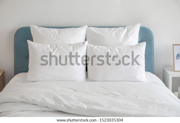 White pillows, duvet and duvet case on a blue bed.\
White bed linen on a blue sofa. Bedroom with bed and bedding. Front\
view.