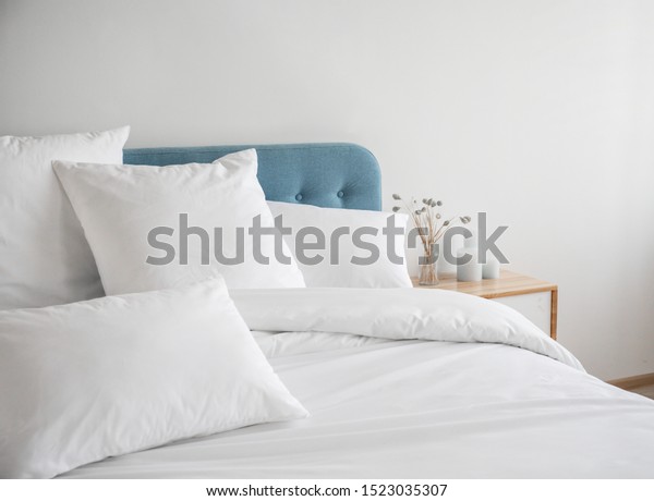 White pillows, duvet and duvet case on a blue bed.\
White bed linen on a blue sofa. Bedroom with bed and bedding. Messy\
bed. Left side view.