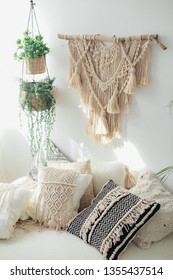 White pillows with macrame. Bed in a minimal bedroom with plants and a round table. Original Macrame. Real photo