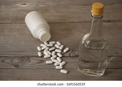 White pills with bottle and bottle of medicine alcohol on wooden table