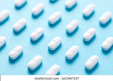 White pills or capsules lies in rows diagonal on blue background