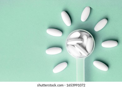 White Pills In Dosage Spoon For Drugs In The Shape Of A Flower On A Aqua Menthe Background, Close-up. Top View, Flat Lay With Copy Space