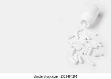 White pills spill out of the bottle.