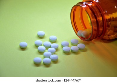 White Pills Spilling Out Of An Orange Pill Bottle On A Chartreuse Background