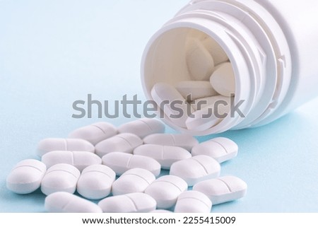 White pills spilling out of pill bottle on white. White pills medicine.