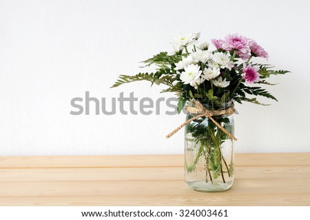 White and pink daisy bouquet in mason jar on table background, fresh flower
